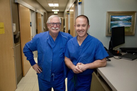 Two urologists standing in clinic, smiling at camera.