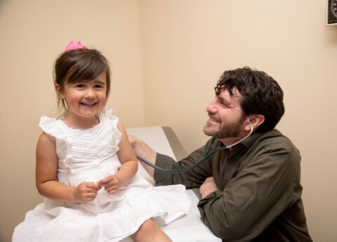 Doctor with young female patient laughing.