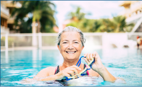 Elderly woman swimming in a pool smiling.