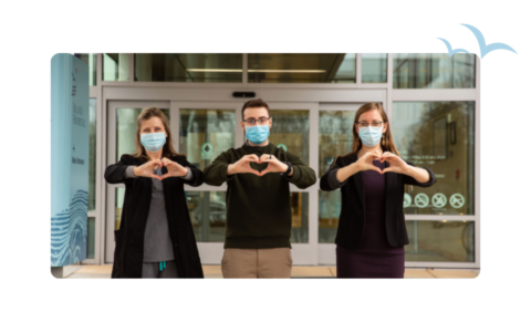 Island Health employees making hearts with their hands in front of main entrance.