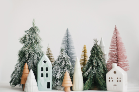 Miniature winter trees with small, porcelain houses set on a white table.