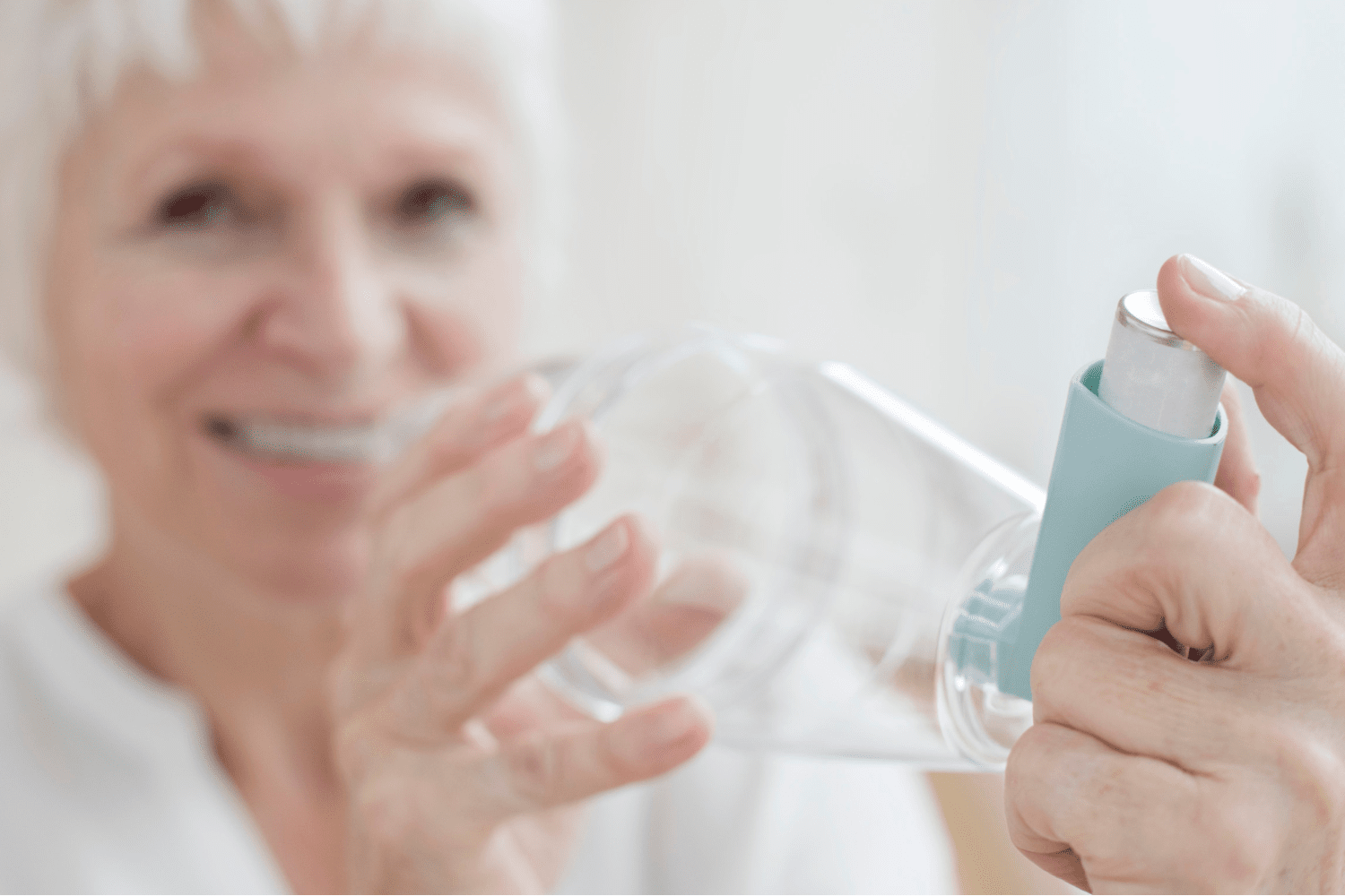 woman smiling and holding inhaler with spacer