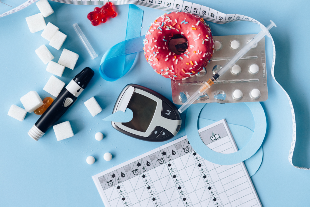 Different diabetes management tools on a table with sugar cubes and a donut.