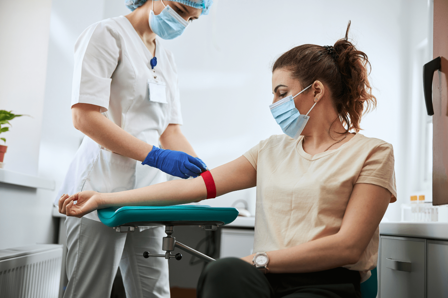 Woman in a beige shirt getting her blood drawn from a healthcare professional.