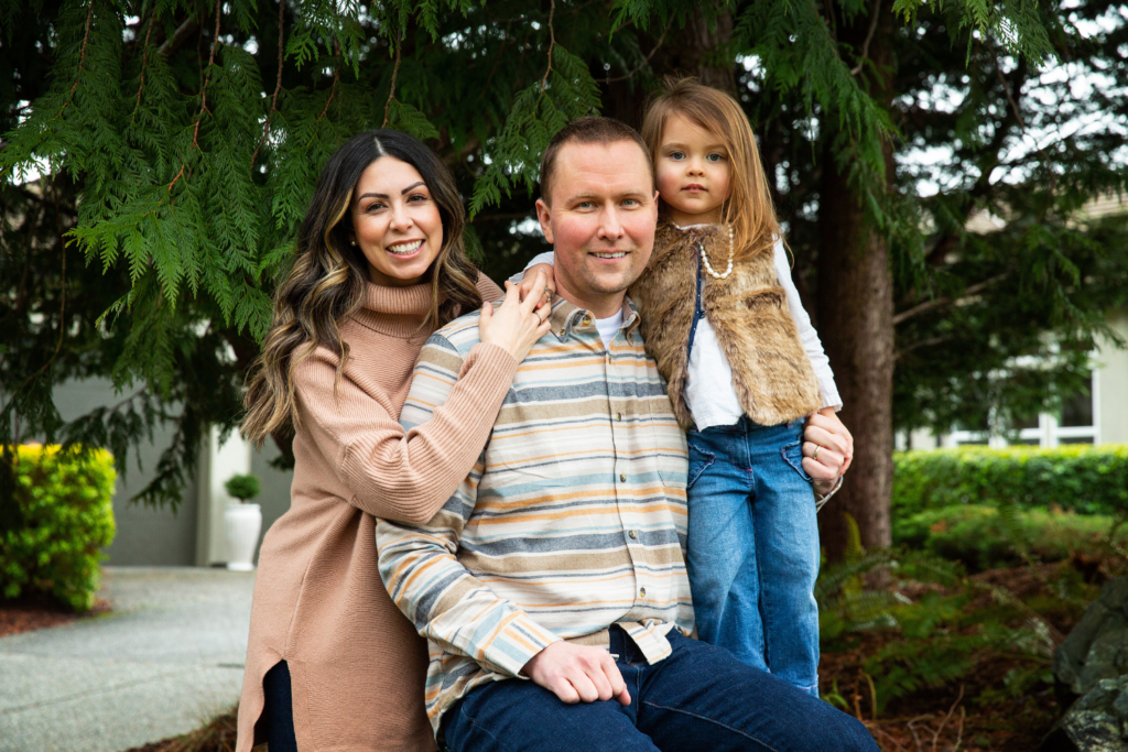 Dr. Krause with his wife and daughter outside sitting on a rock.