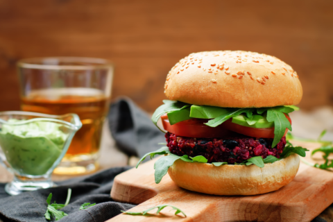 Beet and black bean burger on cutting board with guacamole.