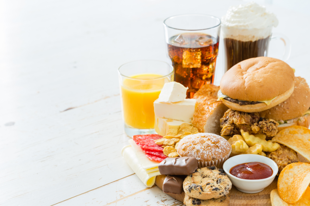 A collection of processed foods including cookies, fries, chips, candy, burgers, soda, juice and fried chicken.