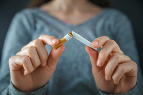 Image of woman in a blue shirt breaking a cigarette apart.