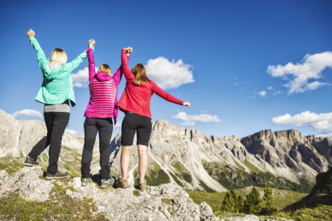 Group of women in mulitcolored jackets hiking.