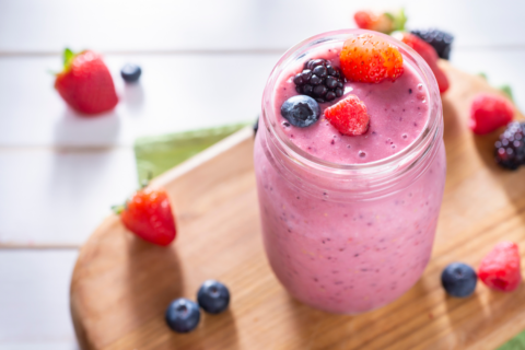 pink mixed berry smoothie on table with fresh berries