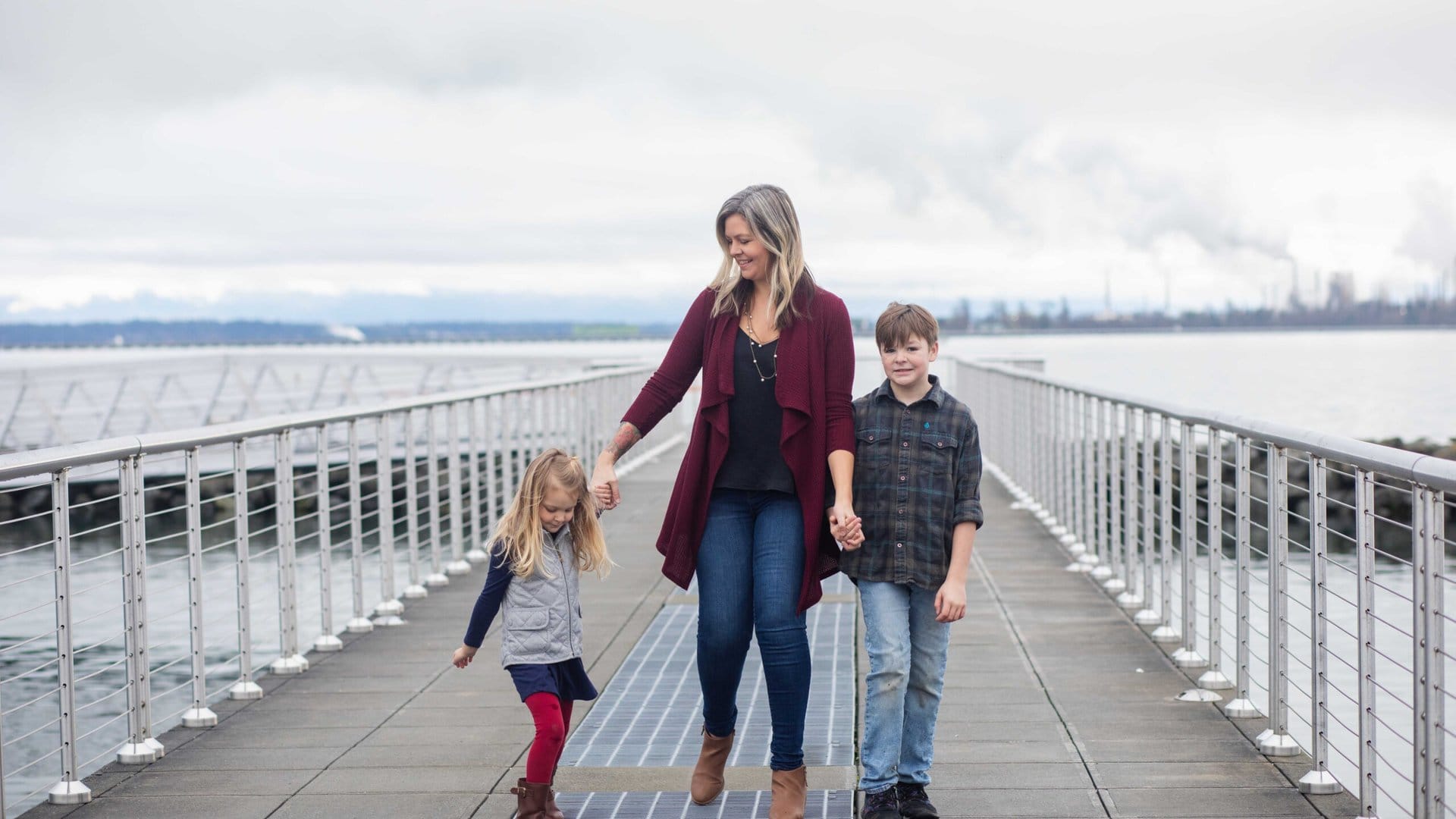 Mom walks with her kids on a bridge.
