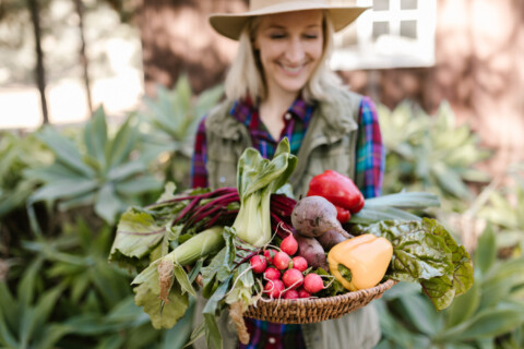 Woman holding basket of fresh vegetables