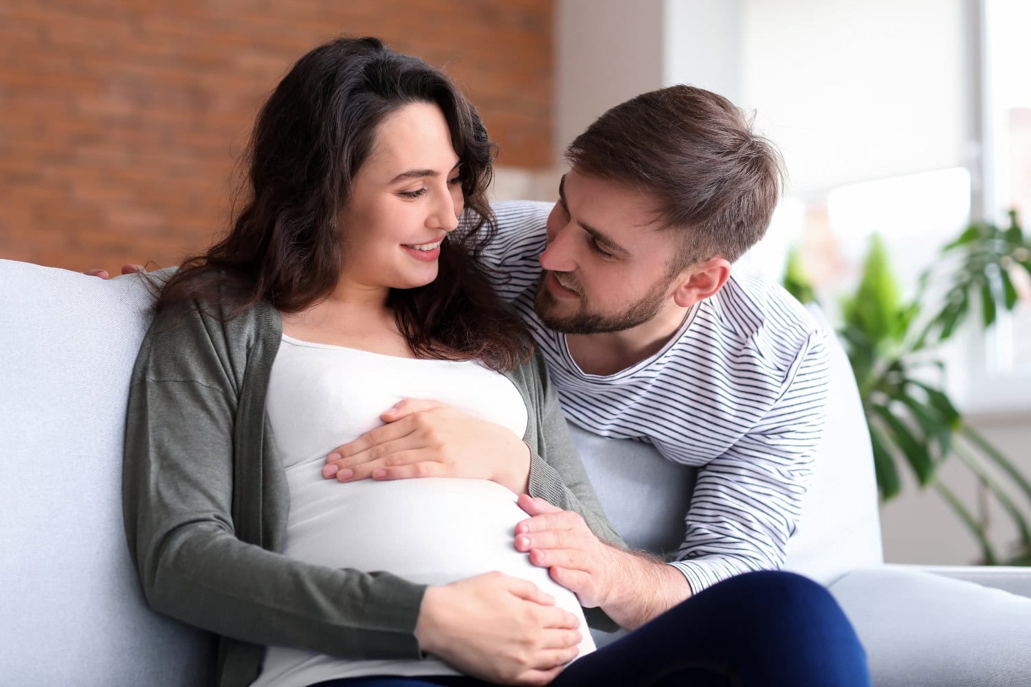 Happy pregnant couple with a brick background