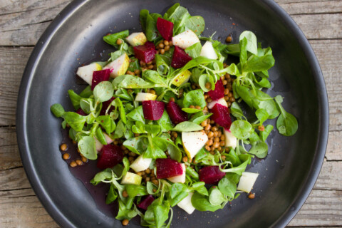 Beet and pear salad on dark plate.