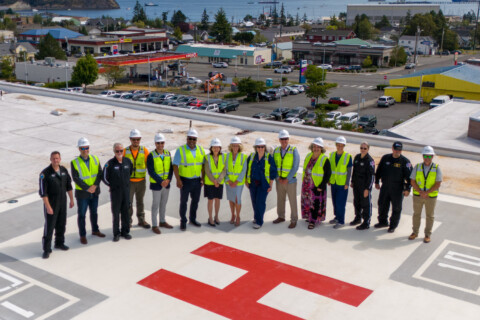 Donors, employees and senators standing on the new rooftop helipad waving.