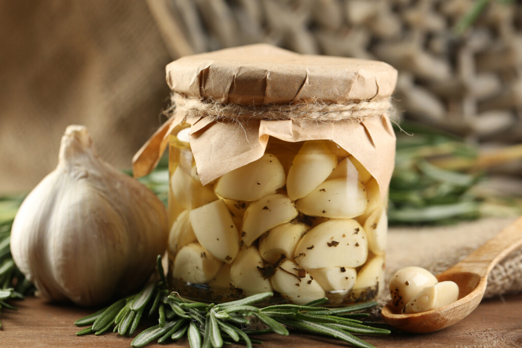 Jar of pickled garlic cloves on wooden cutting board