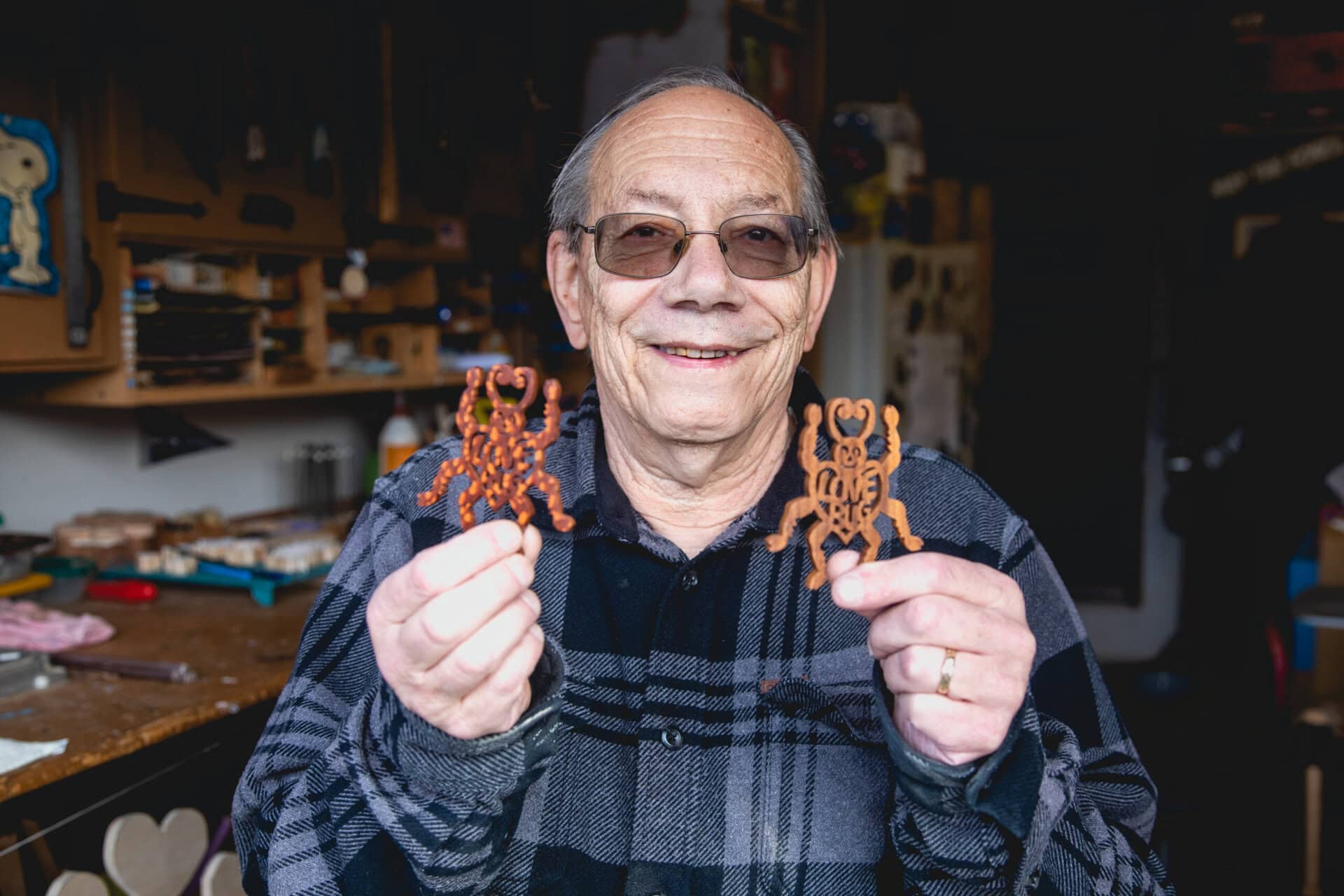 Man holding up two scroll saw projects and smiling.