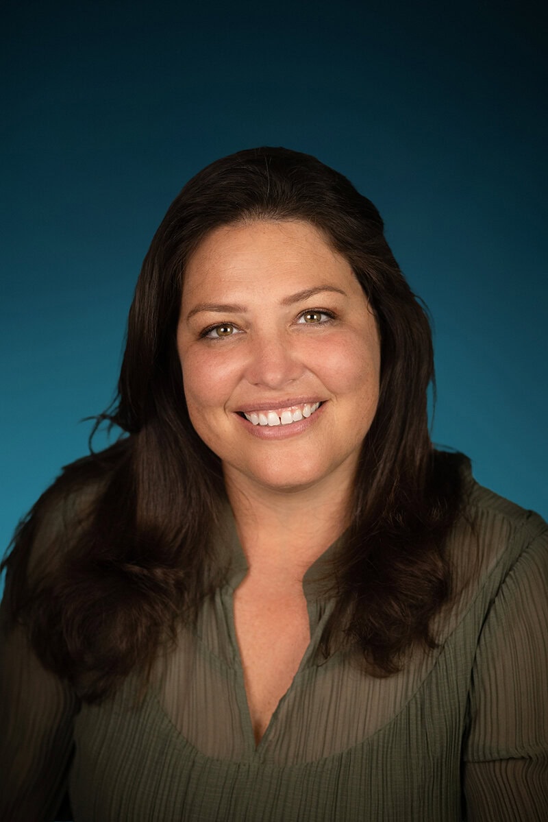 A woman with long brown hair smiling at the camera.