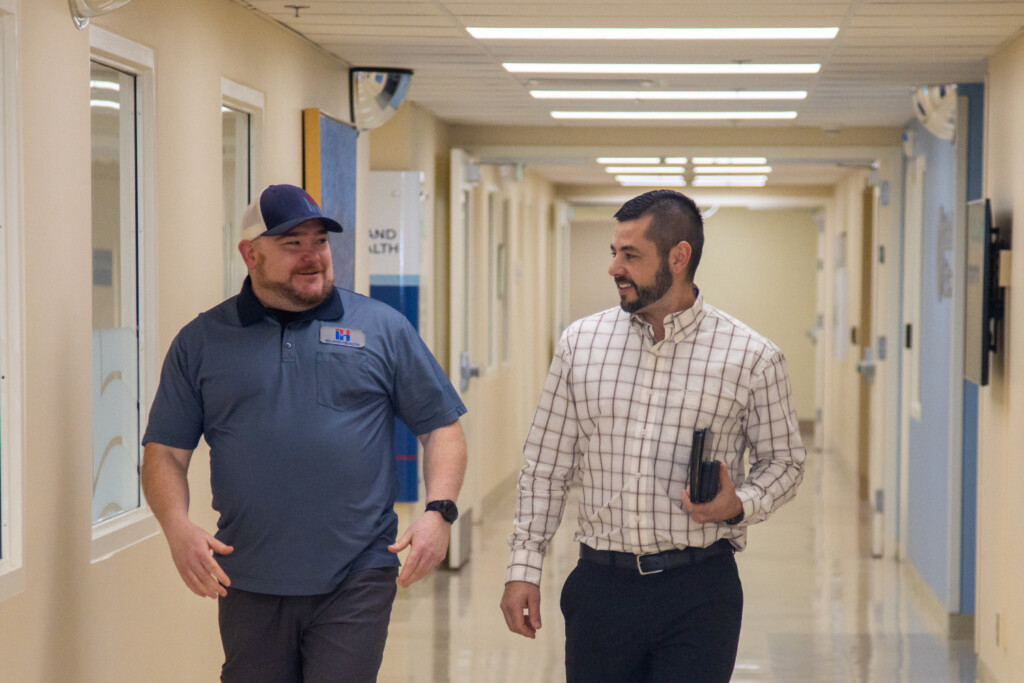 Two men walking down a hallway in conversation.
