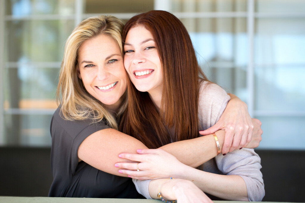 Two generations of women hugging and smiling.