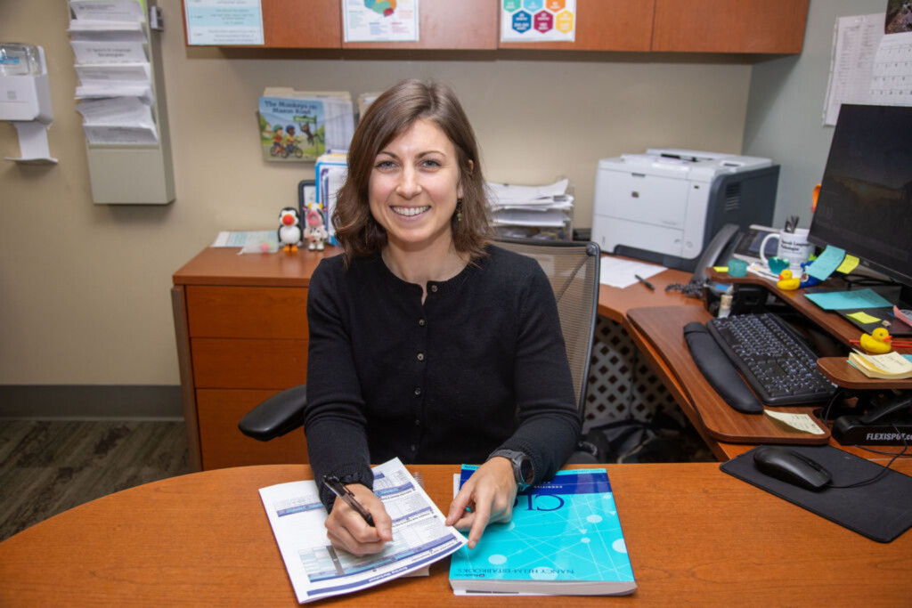 Woman sitting at a desk with paperwork and smiling.