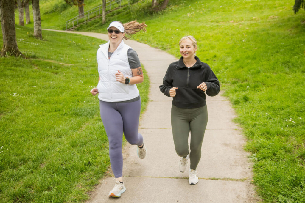 Two women running in the park, smiling.