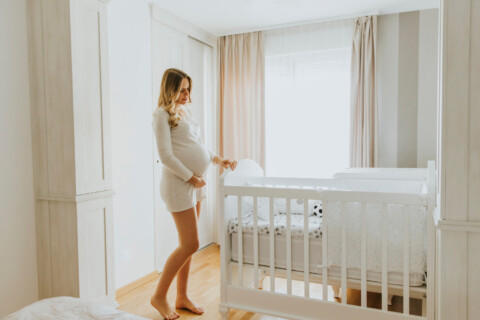 Expectant mother standing in nursery looking at the crib.