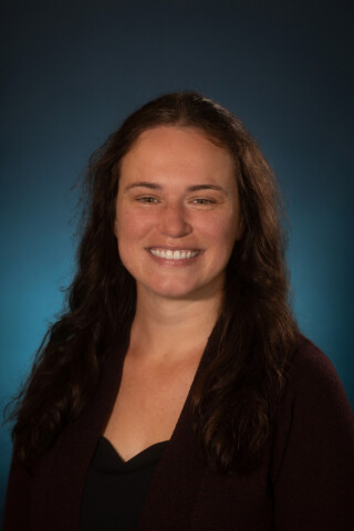 Portrait of Dr. Whitmire, a family medicine physician, wearing a black top, smiling and facing the camera.