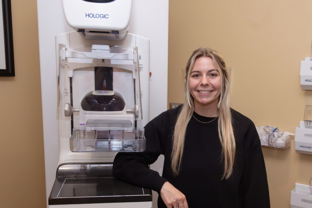 Young woman standing next to a mammography machine.