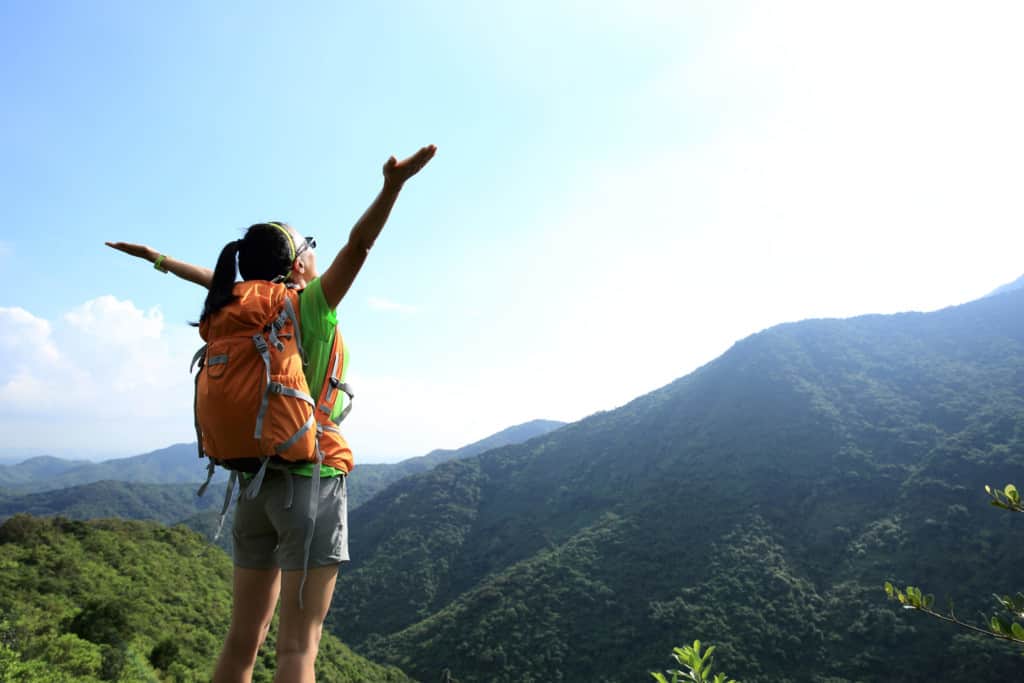 Woman with her hands up in the air, while hiking.