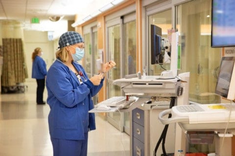 Emergency Department Nurse standing at a computer station, filling medication.