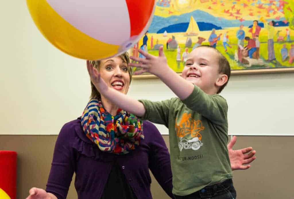 Occupational Therapist with a male pediatric patient playing with a large beach ball.